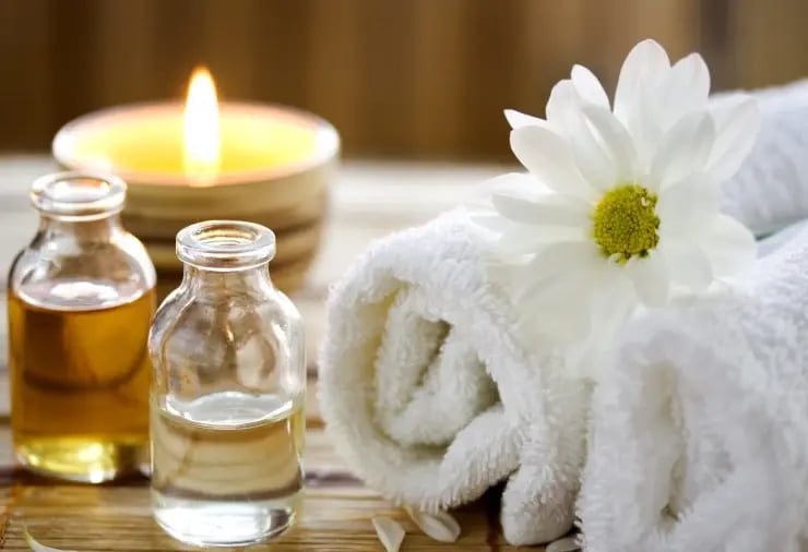 Massage oils, white towel, and daisy flower in a peaceful spa setting.